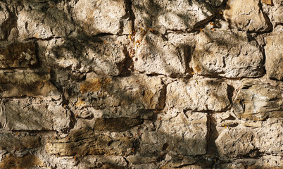 Stone wall, old crumbling stone wall made of stone and sandstone, abstract nature background. Texture of old stone masonry