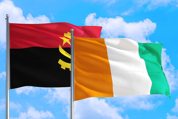 Cote D'Ivoire and Angola national flag waving in the windy deep blue sky. Diplomacy and international relations concept.