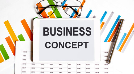 The tablet with text BUSINESS CONCEPT on the business charts and pen