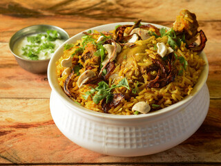 Traditional Hyderabadi Chicken dum Biryani made of Basmati rice cooked with masala spices, served with Onion raita, selective focus