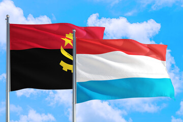 Luxembourg and Angola national flag waving in the windy deep blue sky. Diplomacy and international relations concept.