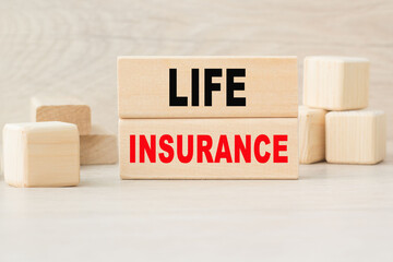 the word LIFE INSURANCE is written on a wooden cubes structure. Cube on a bright background. Can be used for business, marketing, financiaL, INSURANCE concept. Selective focus.