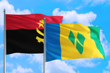 Saint Vincent And The Grenadines and Angola national flag waving in the windy deep blue sky....