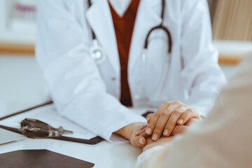 Hands of unknown woman-doctor reassuring her female patient, close-up. Medicine concept