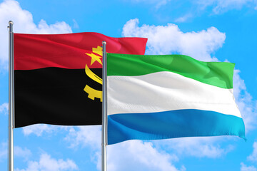 Sierra Leone and Angola national flag waving in the windy deep blue sky. Diplomacy and international relations concept.