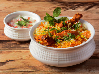 Traditional Hyderabadi Chicken dum Biryani made of Basmati rice cooked with masala spices, served with Onion raita, selective focus