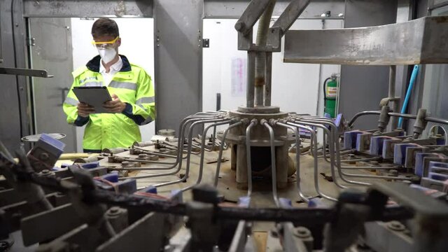 Engineer wearing face mask and protection glasses holding clipboard checking automatic machine in industry manufacturing factory. worker maintenance
