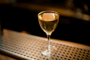 transparent wine glass with alcoholic drink stands on the bar counter