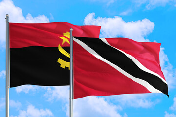 Trinidad And Tobago and Angola national flag waving in the windy deep blue sky. Diplomacy and international relations concept.