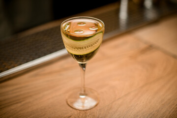 view of glass with drink decorated with slice of cucumber stands on wooden surface