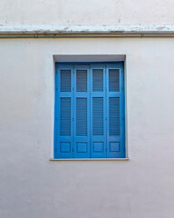 Fototapeta premium Greece, closed blue shutters window on old plastered wall, some space for text