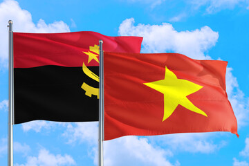 Vietnam and Angola national flag waving in the windy deep blue sky. Diplomacy and international relations concept.