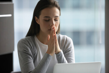 I wish to goodness. Worried young female student sitting by computer praying for luck expecting...