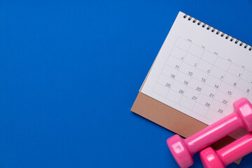 Time for exercising calendar and dumbbell with blue background, sport and healthy concept