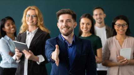 Welcome on board. Portrait of positive confident millennial male hr manager leader of multiethnic team looking at camera extending hand for handshake greeting new staff member inviting newbie to join