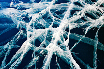 Beautiful transparent blue ice with cracks, top view. Lake Baikal in winter. Natural cold background of ice