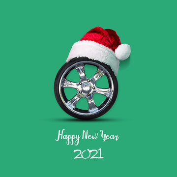 Car wheel in the hat of Santa Claus, on a green background. Congratulations to the car repair shop, car shop.