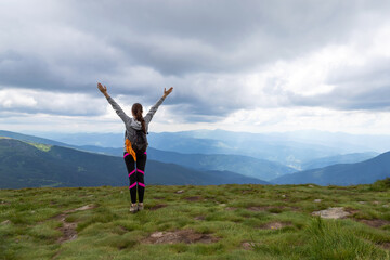 Sporty, happy girl with raised arms on the top of the mountain. Tourism.