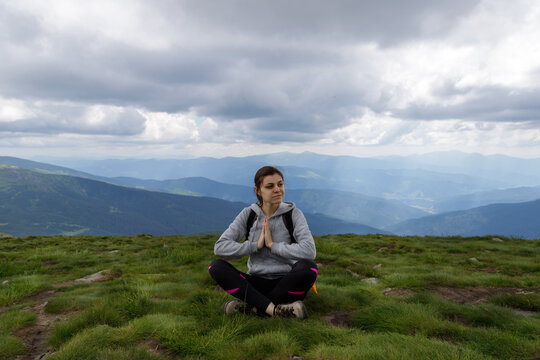 Young girl on the grass, surrounded by beautiful mountains. Tourism. T