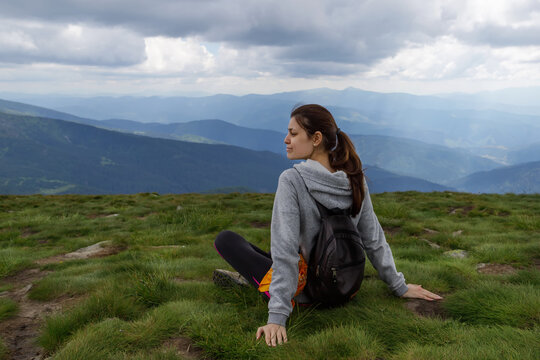 Young girl on the grass, surrounded by beautiful mountains. Tourism. T