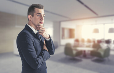 Thoughtful young businessman in office, side view