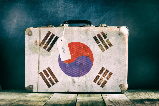 Old suitcase with Korea flag on wooden background.