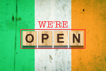 Obraz premium We are open. The inscription on wooden blocks against the background of the flag of Ireland. Business.