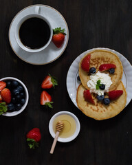 Pancakes with strawberries and blueberries and honey. Top view.