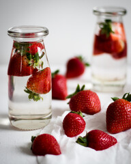 Strawberries in water in glass bottles on a light background