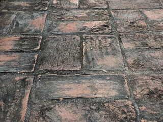 Old brick walkway in closeup, covered with dust and small rocks