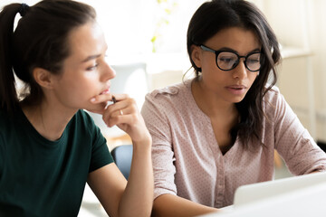 Difficult task. Pensive concentrated caucasian and biracial young female students colleagues...