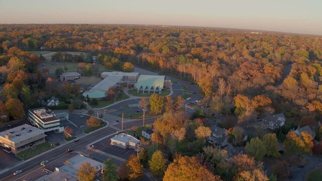Aerial flyover middle school and then to the neighborhood beyond itl in Ladue, Missouri with gorgeous Fall trees at near peak color and a beautiful hombre sky on the horizon.
