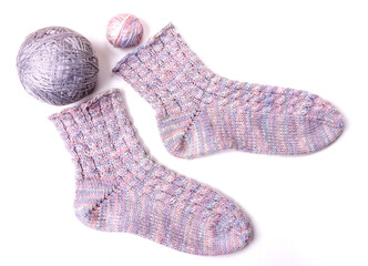 A pair of knitted light wool socks. There are two balls of wool next to it. Isolated on white background.