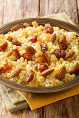 Mesfouf is a steamed Couscous with olive oil, butter, nuts and raisins close-up in a plate on the table. vertical