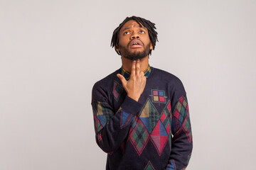 Obraz premium Deeply depressed frustrated african man with dreadlocks holding fingers in gun shape under his head, going to commit suicide, mental problems, crisis. Indoor studio shot isolated on gray background