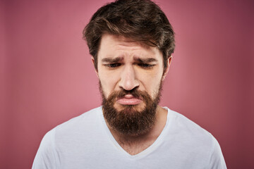 Fototapeta premium Emotional bearded man in white T-shirt discontent pink background