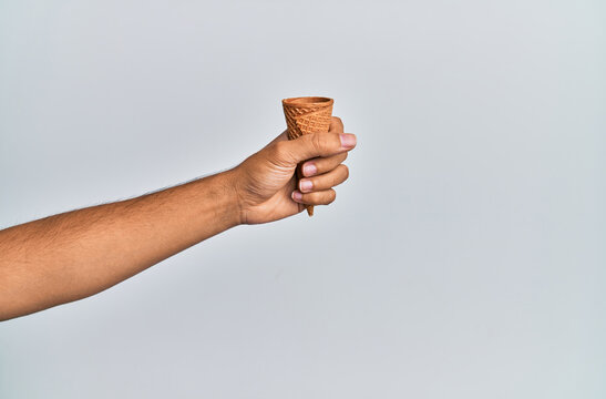 Hand of hispanic man holding biscuit cone over isolated white background.