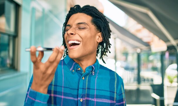 Young african american man sending audio message using smartphone at street of city.