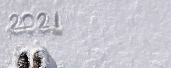 top view on 2020 hand writing on the snow with hiker foot in panoramic size