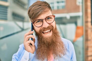 Young redhead businessman smiling happy and talking on the smartphone standing at the city.