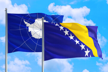Bosnia Herzegovina and Antarctica national flag waving in the windy deep blue sky. Diplomacy and international relations concept.