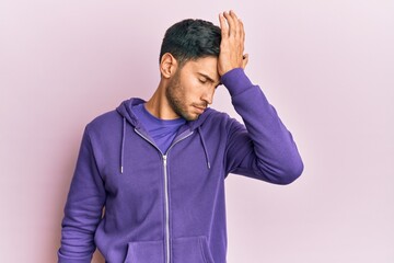 Young handsome man wearing casual sweatshirt surprised with hand on head for mistake, remember...