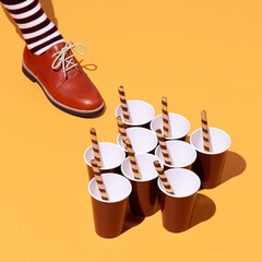 Leg in vintage striped socks and shoes in stylish isometric sweet cups space. Minimal still life food art. Chocolate lover. Holidays party time, winter christmas celebration season