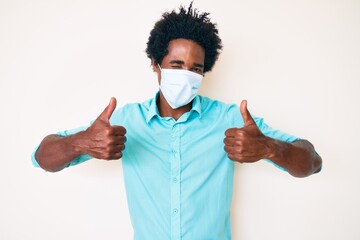 Handsome african american man with afro hair wearing medical mask winking looking at the camera...