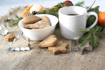 Mug with coffee, homemade Christmas pastries, cookie cutters on a blurred background. New Year's composition.