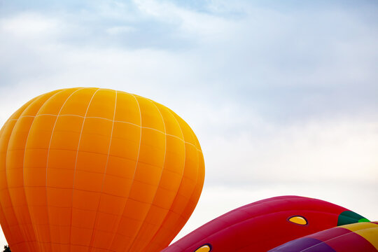 two balloons of orange and red against the cloudy sky