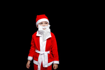a five-year-old boy in a funny Santa Claus costume stands with a package of gifts. on a black isolated background
