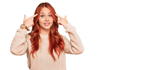 Fototapeta na wymiar Young redhead woman wearing casual winter sweater smiling pointing to head with both hands finger, great idea or thought, good memory