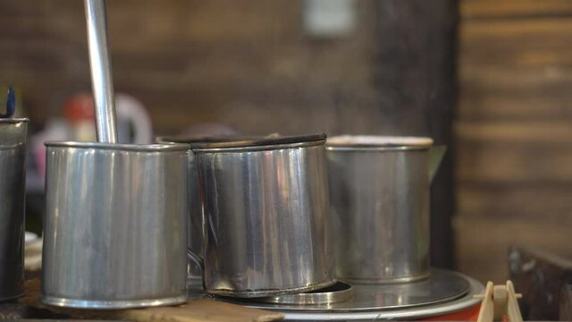 Traditional coffee dripper equipment or teh tarik and tea with aroma smoke by hot steam on old steel pot with filter cloth in cafe shop for morning drink or beverage and fresh breakfast on retro style