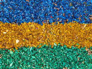 Painted wood shavings for flower bed decoration and soil drainage. Blue, yellow, and green layers.